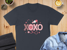 Load image into Gallery viewer, Dark t-shirt with pink "XOXO" design featuring stethoscope, pill, and heart pattern.