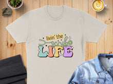 Load image into Gallery viewer, Light cream t-shirt with colorful "Livin' the Scrub Life" text.