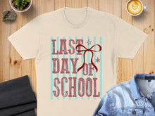Load image into Gallery viewer, T-shirt with "Last Day of School" text and red bow on striped background.