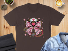 Load image into Gallery viewer, Brown t-shirt with pink bow, stethoscope, and heart graphic.