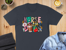 Load image into Gallery viewer, Dark t-shirt with "NURSE LIFE" text, coffee cup, and medical icons.