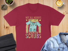 Load image into Gallery viewer, Maroon t-shirt with rainbow and text: Not all heroes wear capes, some wear scrubs.