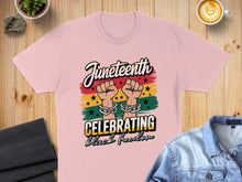 Load image into Gallery viewer, Juneteenth t-shirt with chained fists and celebratory text on striped background.