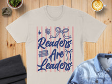 Load image into Gallery viewer, Light t-shirt with "Readers Are Leaders" in blue text and decorative elements.