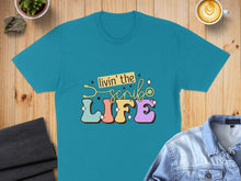 Load image into Gallery viewer, Teal t-shirt with colorful "Livin' the Scrub Life" text and stethoscope.