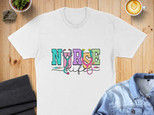 Load image into Gallery viewer, White t-shirt with "Nurse Life" text in colorful block letters and stethoscope graphic.