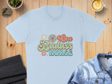 Load image into Gallery viewer, Light blue t-shirt with "One Badass Nurse" text and floral graphics.