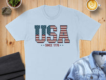Load image into Gallery viewer, Light blue t-shirt with "USA SINCE 1776" in red, white, and blue flag design.