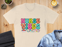 Load image into Gallery viewer, Cream t-shirt with "NURSE VIBES" text and medical icons.