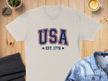 Load image into Gallery viewer, Cream t-shirt with "USA EST. 1776" printed in blue and red.