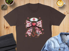 Load image into Gallery viewer, Brown t-shirt featuring a pink bow with stethoscope, hearts, and medical symbols.