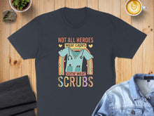 Load image into Gallery viewer, Dark t-shirt with "Not all heroes wear capes, some wear scrubs" and stethoscope graphic.