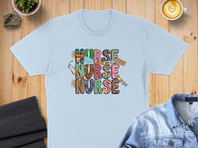 Load image into Gallery viewer, Light blue t-shirt with colorful "Nurse Nurse" text and medical icons.