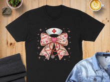 Load image into Gallery viewer, Black t-shirt with a pink bow design featuring a stethoscope, hearts, and a nurse's cap.