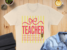 Load image into Gallery viewer, Cream t-shirt with "TEACHER" and motivational text, framed by yellow stripes.