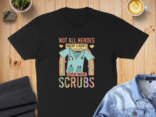 Load image into Gallery viewer, Black t-shirt with "Not all heroes wear capes, some wear scrubs" quote and stethoscope.