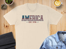 Load image into Gallery viewer, Cream t-shirt with "AMERICA EST. 1776" in red, white, and blue text.