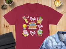 Load image into Gallery viewer, Burgundy t-shirt with a colorful school-themed graphic of a bus, globe, and art supplies.