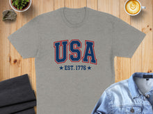Load image into Gallery viewer, Gray t-shirt with "USA EST. 1776" in blue and red text.