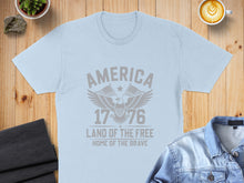 Load image into Gallery viewer, Light blue t-shirt with "America 1776 Land of the Free Home of the Brave" and an eagle graphic.