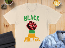 Load image into Gallery viewer, Cream t-shirt with "Black Lives Matter" fist graphic and text.