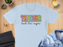 Load image into Gallery viewer, Light blue t-shirt with "TEACHER" in colorful polka dots and "teach love inspire" below.