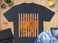 Load image into Gallery viewer, Dark t-shirt with "Lunch Day" in orange text on a pink striped background.