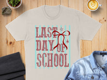 Load image into Gallery viewer, Cream t-shirt with "LAST DAY OF SCHOOL" text, red bow, and blue stripes.