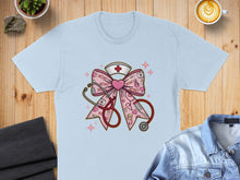 Load image into Gallery viewer, Light blue t-shirt featuring a pink bow with stethoscope, heart, and XOXO nurse graphics.