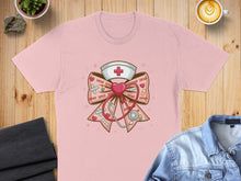 Load image into Gallery viewer, Pink t-shirt with a nurse's hat and stethoscope graphic forming a bow.
