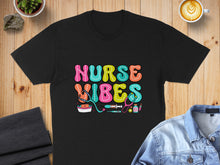 Load image into Gallery viewer, Black t-shirt with colorful "Nurse Vibes" text and medical icons.