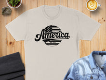 Load image into Gallery viewer, Cream t-shirt with black "America Est. 1776" text and American flag circle graphic.