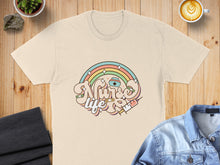 Load image into Gallery viewer, Cream t-shirt with "Nurse Life" text, rainbow, and syringe graphic.