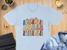 Load image into Gallery viewer, Light blue t-shirt with "Nurse Nurse Nurse" text in groovy, floral font.