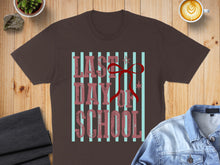 Load image into Gallery viewer, Brown t-shirt with "Last Day of School" text and red ribbon design.