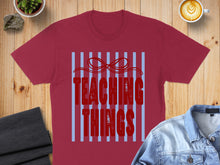 Load image into Gallery viewer, Burgundy t-shirt with "Teaching Things" graphic and a red bow.