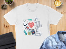 Load image into Gallery viewer, White t-shirt with stethoscope, syringe, and pills graphic and text "she works willingly with her hands".
