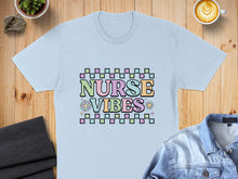 Load image into Gallery viewer, Light blue t-shirt with "Nurse Vibes" text in pastel checkered blocks and floral accents.