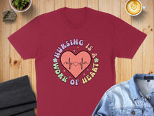 Load image into Gallery viewer, Burgundy t-shirt with "Nursing is a work of heart" graphic and heartbeat line.