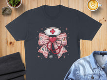 Load image into Gallery viewer, Dark t-shirt with a stethoscope, heart, and nurse's cap graphic.