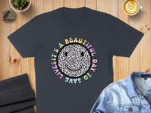 Load image into Gallery viewer, Dark t-shirt with a leopard print smiley face graphic and text.