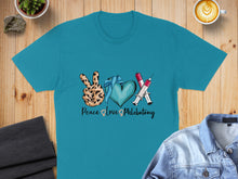 Load image into Gallery viewer, Teal t-shirt with peace sign, heart, and syringes, text "Peace Love Phlebotomy".