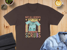 Load image into Gallery viewer, Brown t-shirt with "Not all heroes wear capes, some wear scrubs" and stethoscope.