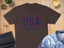 Load image into Gallery viewer, Brown t-shirt with "USA EST. 1776" in blue and red lettering.