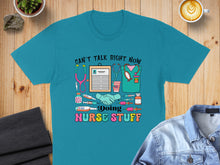 Load image into Gallery viewer, Teal t-shirt with "Can't talk right now, doing nurse stuff" and medical graphics.