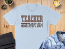 Load image into Gallery viewer, Light blue t-shirt with "TEACHER" and lightning bolt graphics, and text.