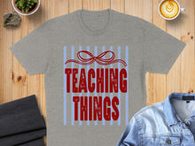 Load image into Gallery viewer, Grey t-shirt with "TEACHING THINGS" in red text on blue stripes.