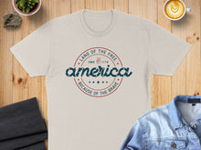 Load image into Gallery viewer, Light beige t-shirt with "Land of the Free, Since 1776, America, Because of the Brave" text.