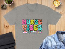 Load image into Gallery viewer, Grey t-shirt with colorful "Nurse Vibes" text and medical icons.