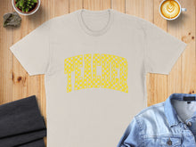 Load image into Gallery viewer, Cream t-shirt with yellow checkered "TEACHER" text, styled on a wooden surface.